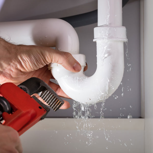 man working on leaking plumbing